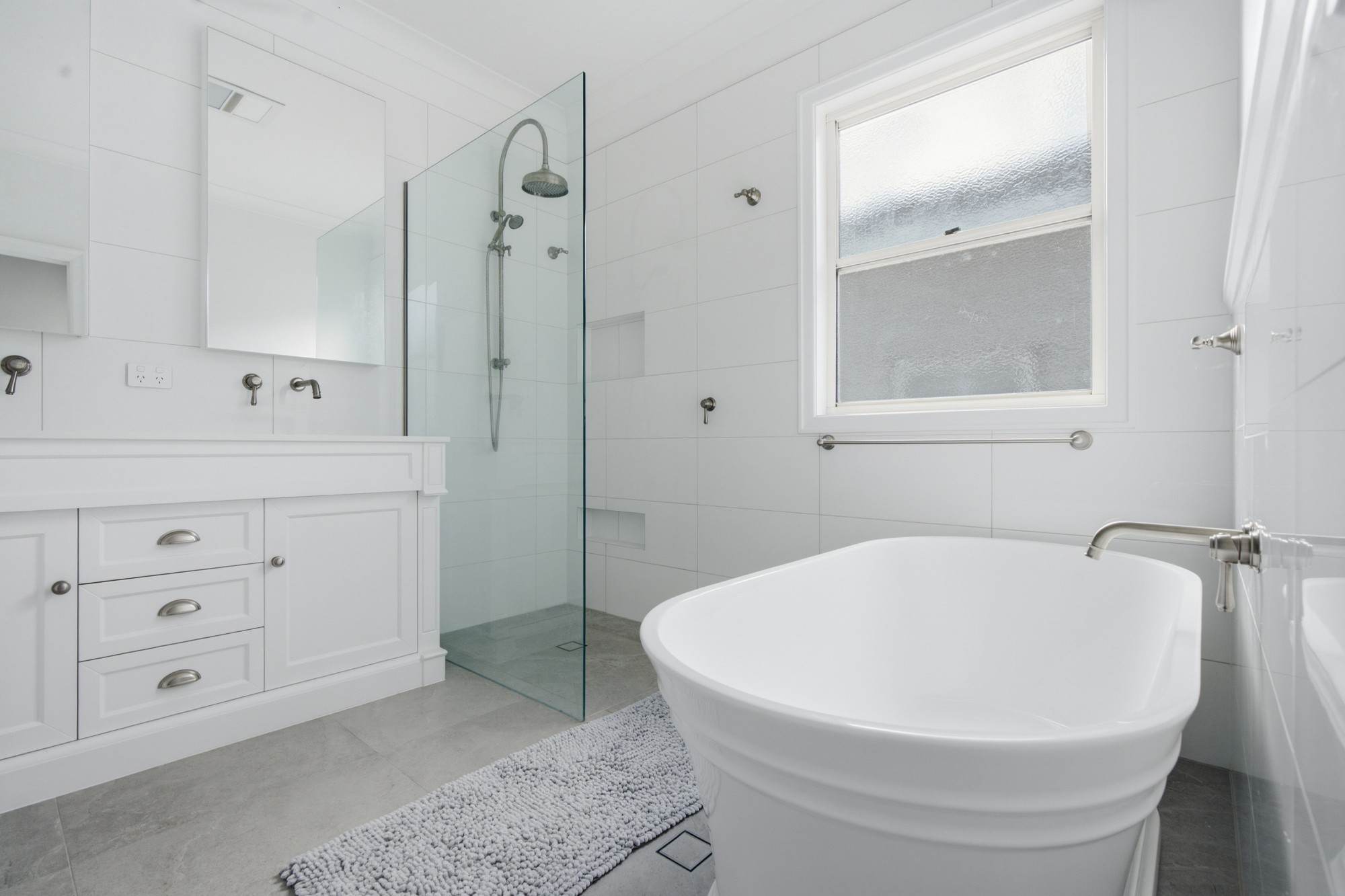 Classic white bathroom with freestanding bath, walk-in shower and shaker vanity