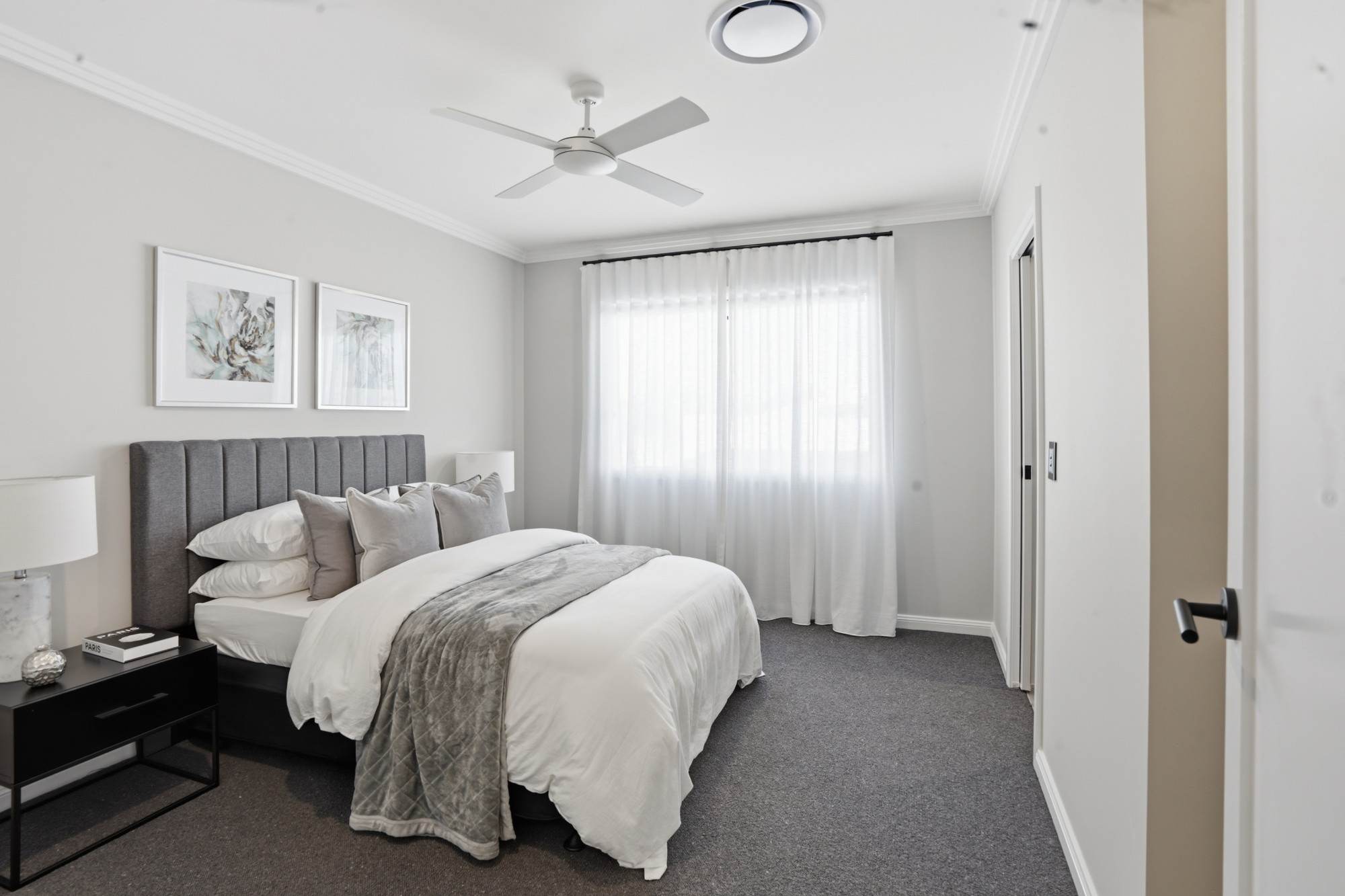 Bedroom with grey channelled headboard and ceiling fan
