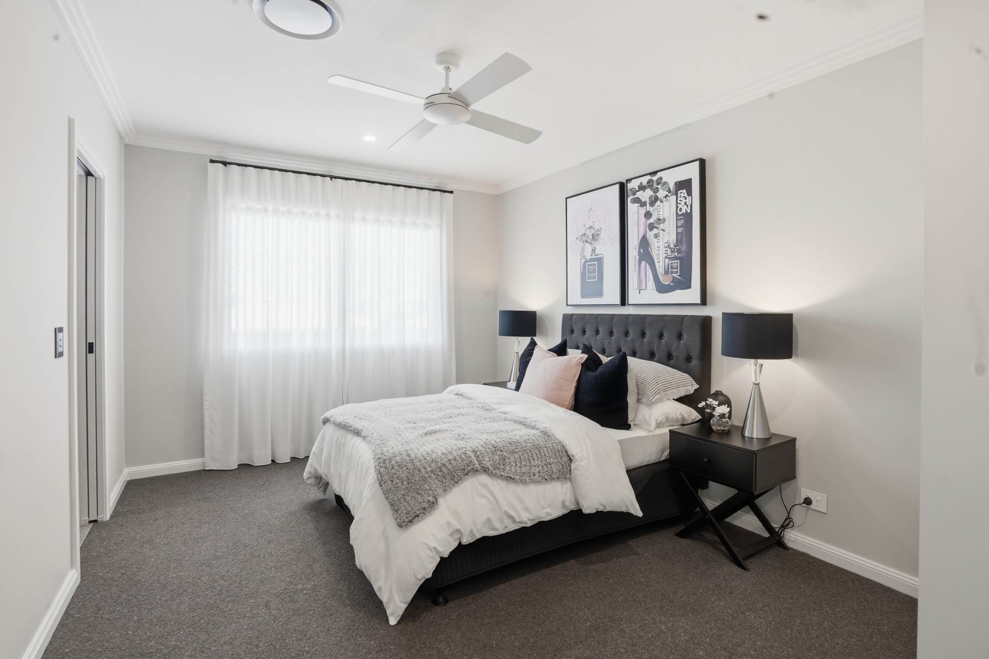 Bedroom with buttoned headboard, black lamps and fashion prints
