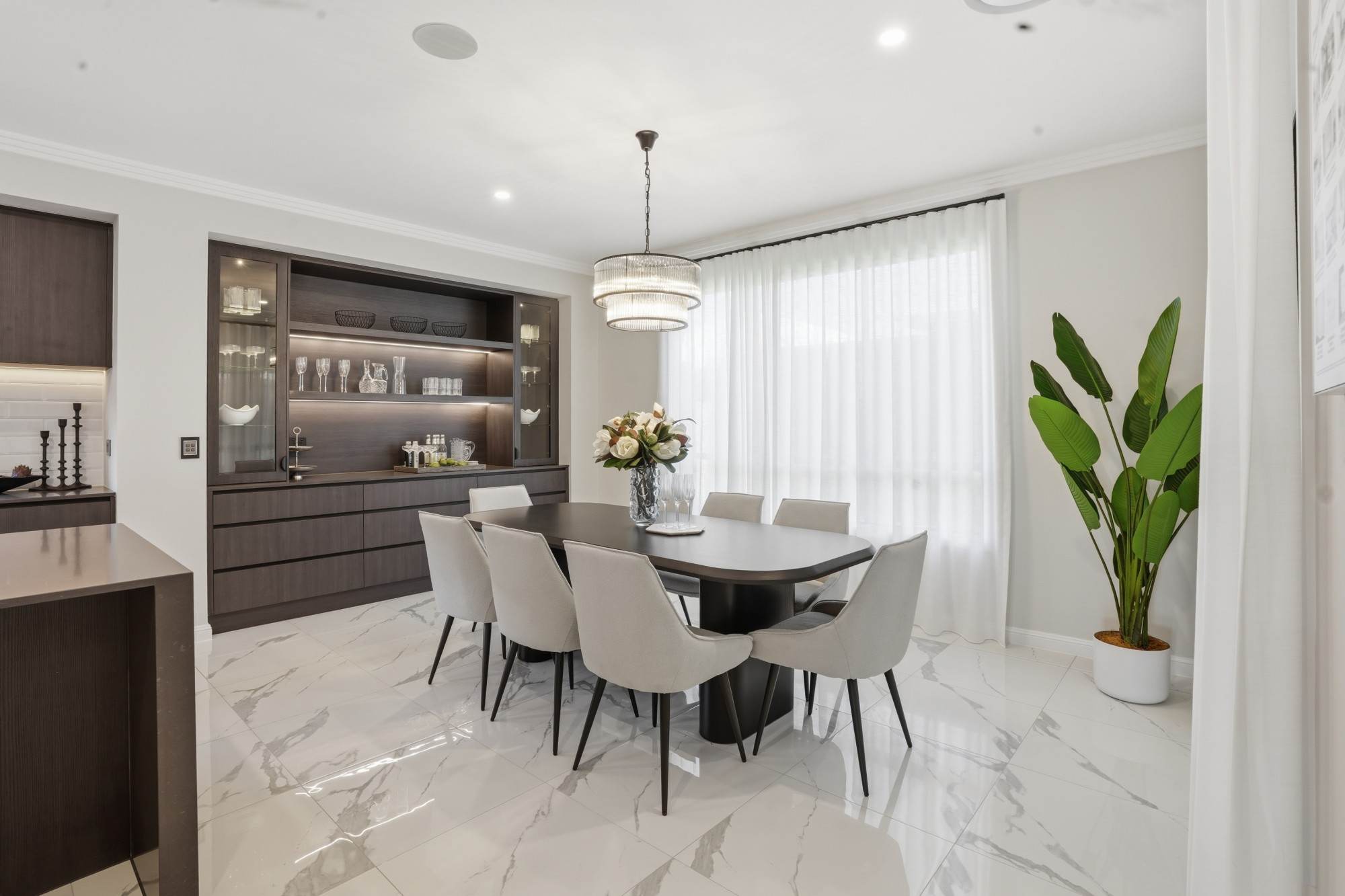 Dining room with oval table, crystal pendant and backlit timber cabinetry