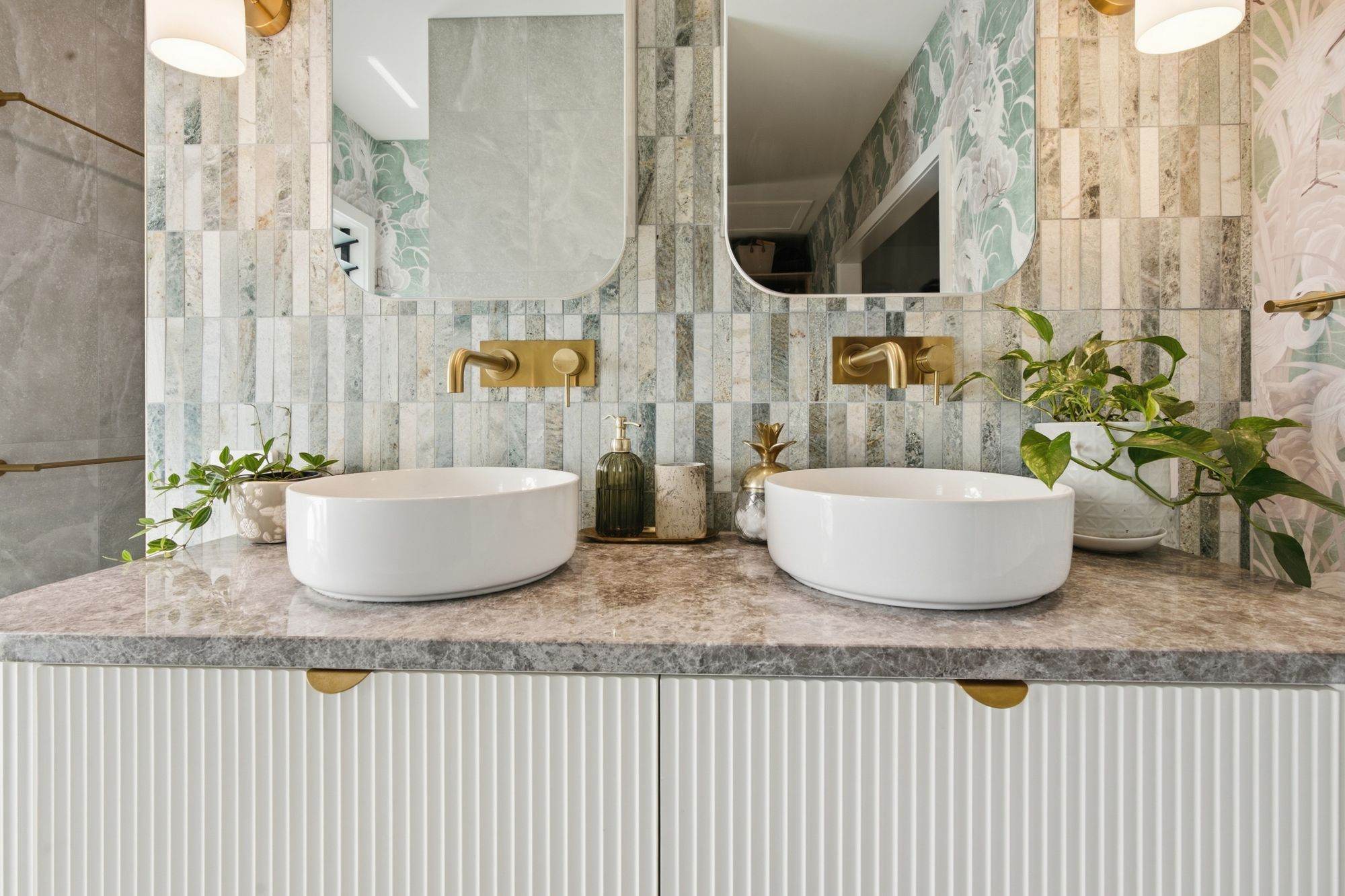 Double vanity with vessel basins, brushed brass tapware and green stone mosaic splashback