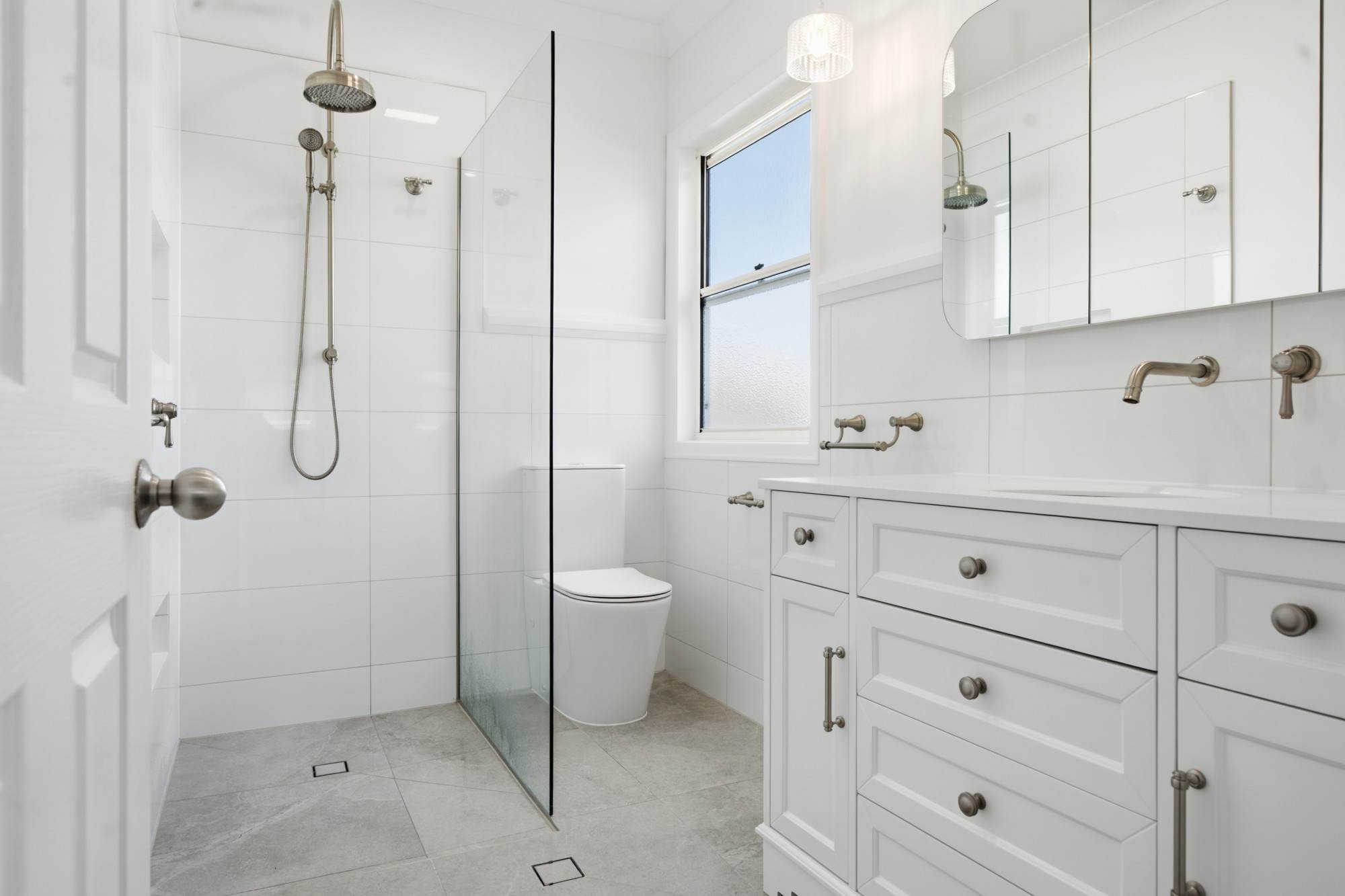 Bright ensuite with rain shower, frameless glass and shaker vanity
