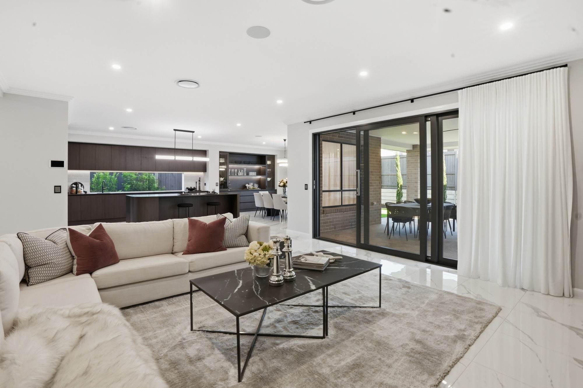Family room opening through black-framed sliding doors to the alfresco