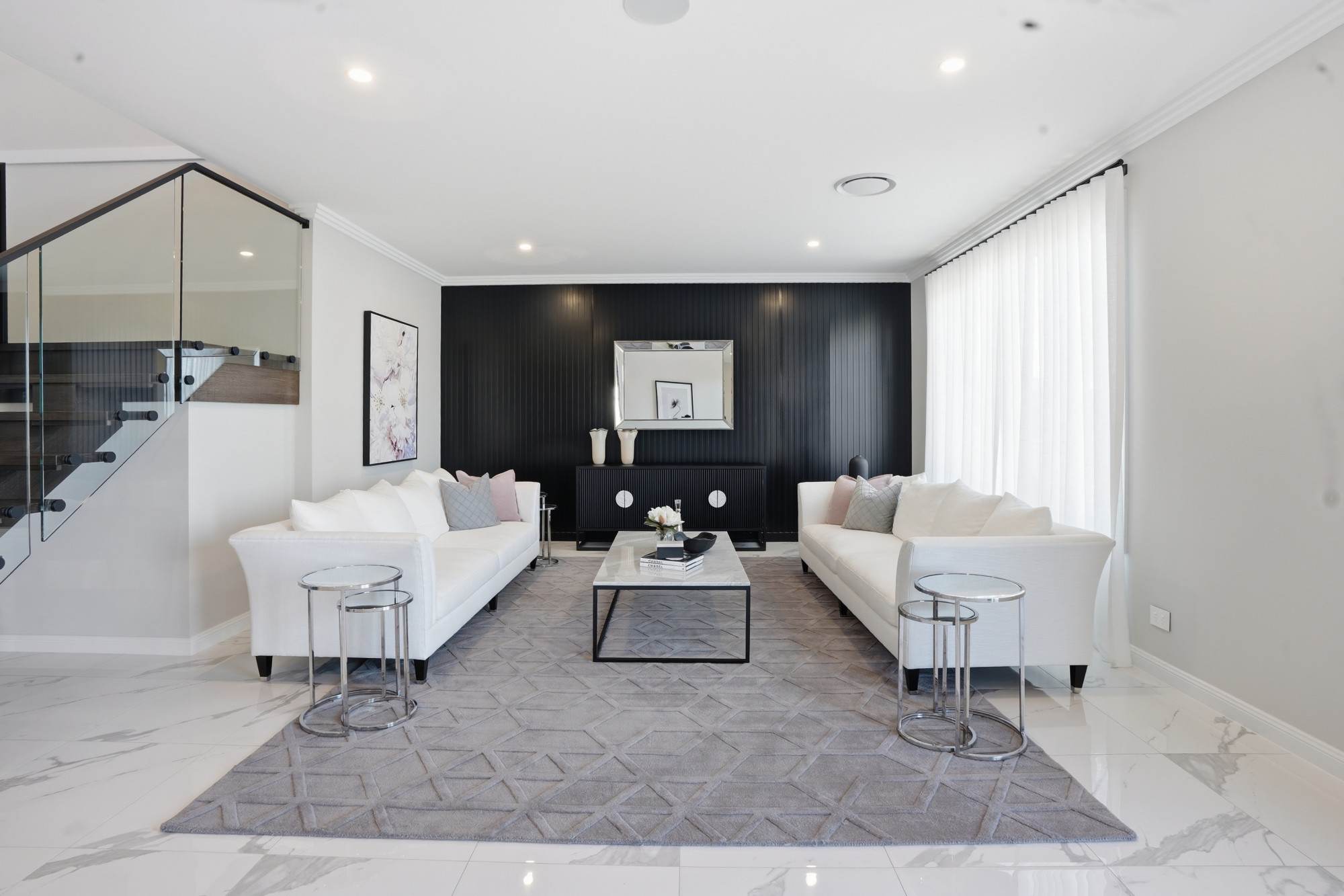 Symmetrical formal lounge with twin white sofas against a black panelled feature wall