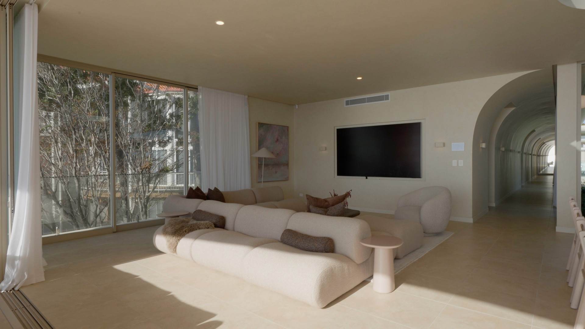 Living room with modular sofa beside a long arched gallery hallway