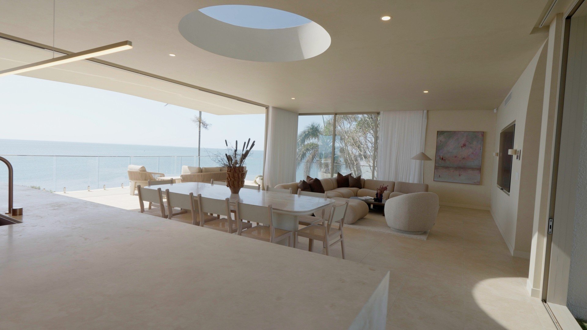 Open-plan living at Horizon by Graya under a circular skylight, opening to a balcony over the bay