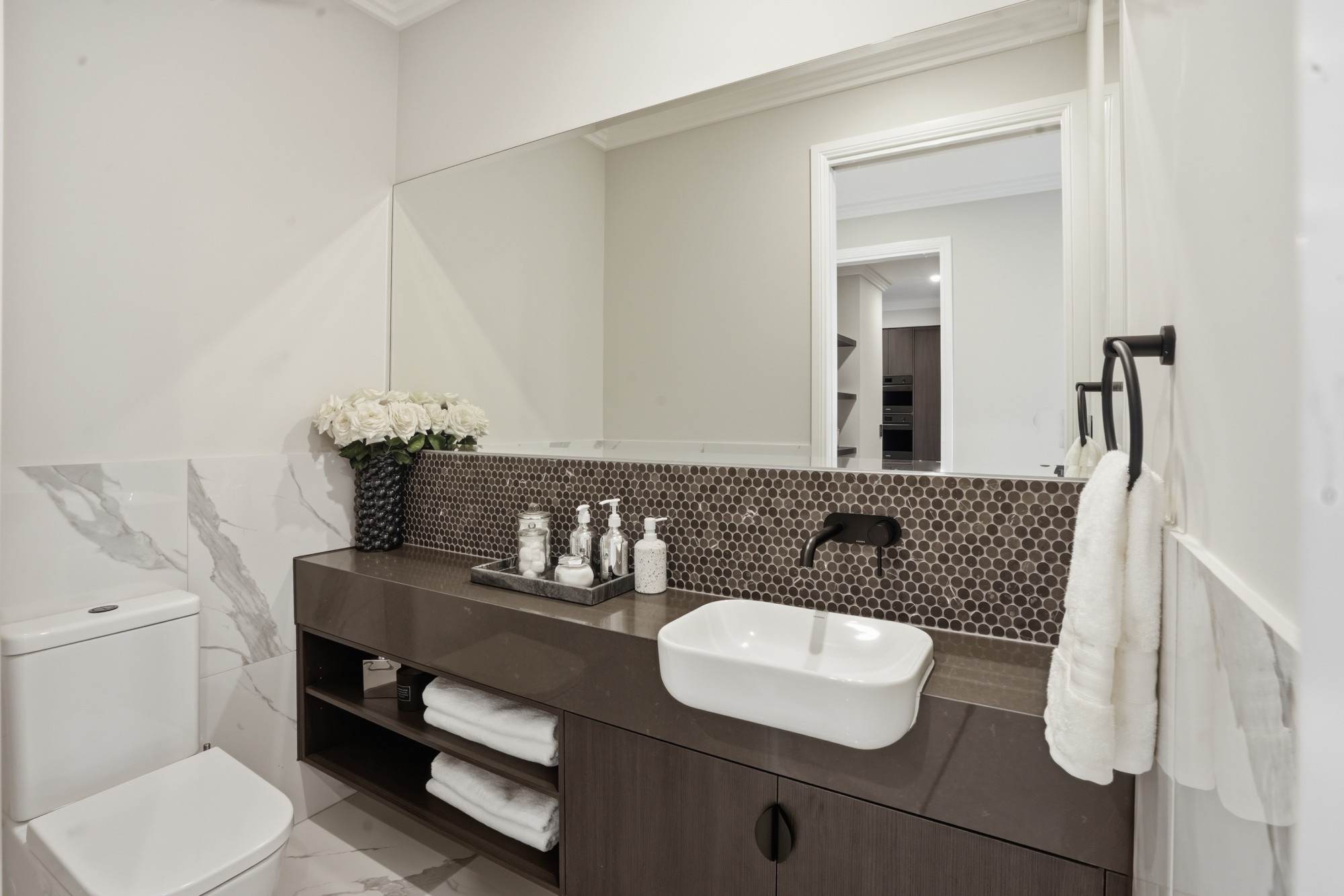 Powder room with penny round mosaic splashback, stone vanity and matte black tapware