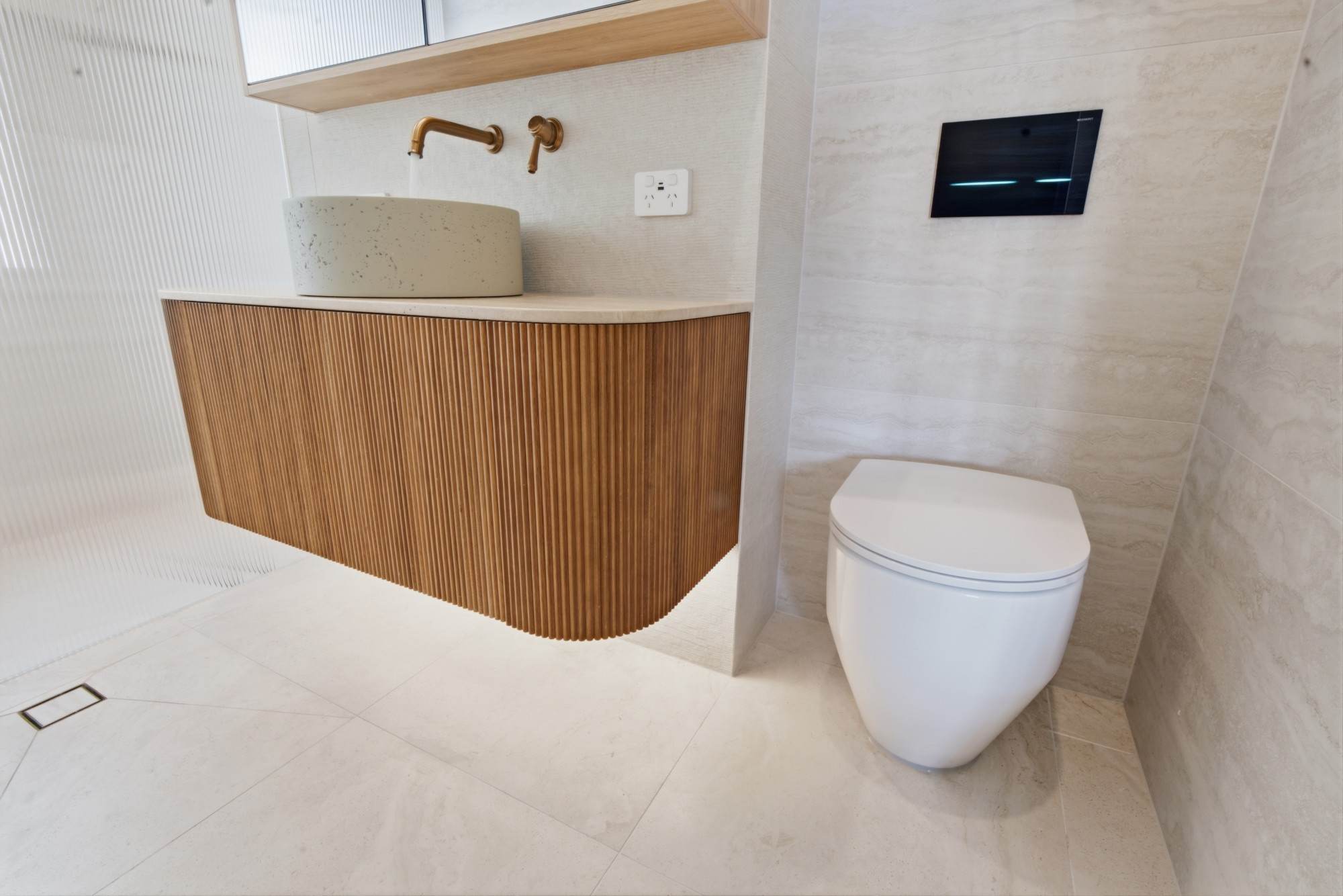 Floating fluted timber vanity with concrete vessel basin and wall-hung toilet